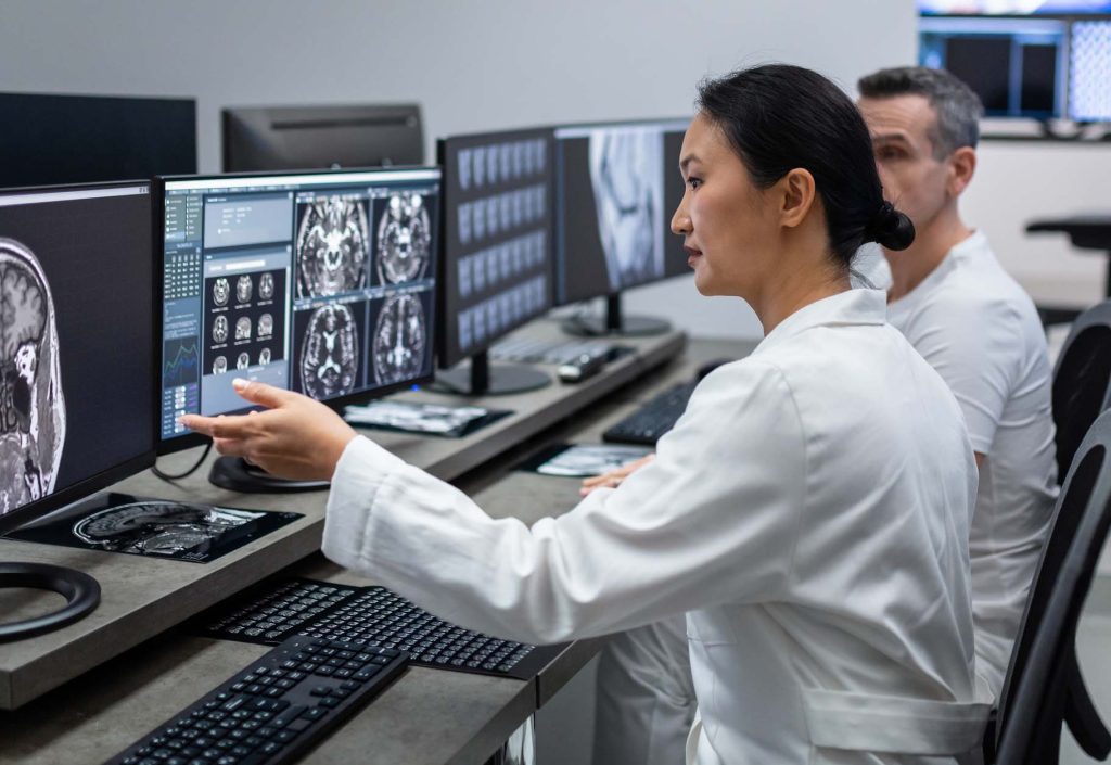 Two radiologists looking at MRI scan on computer.