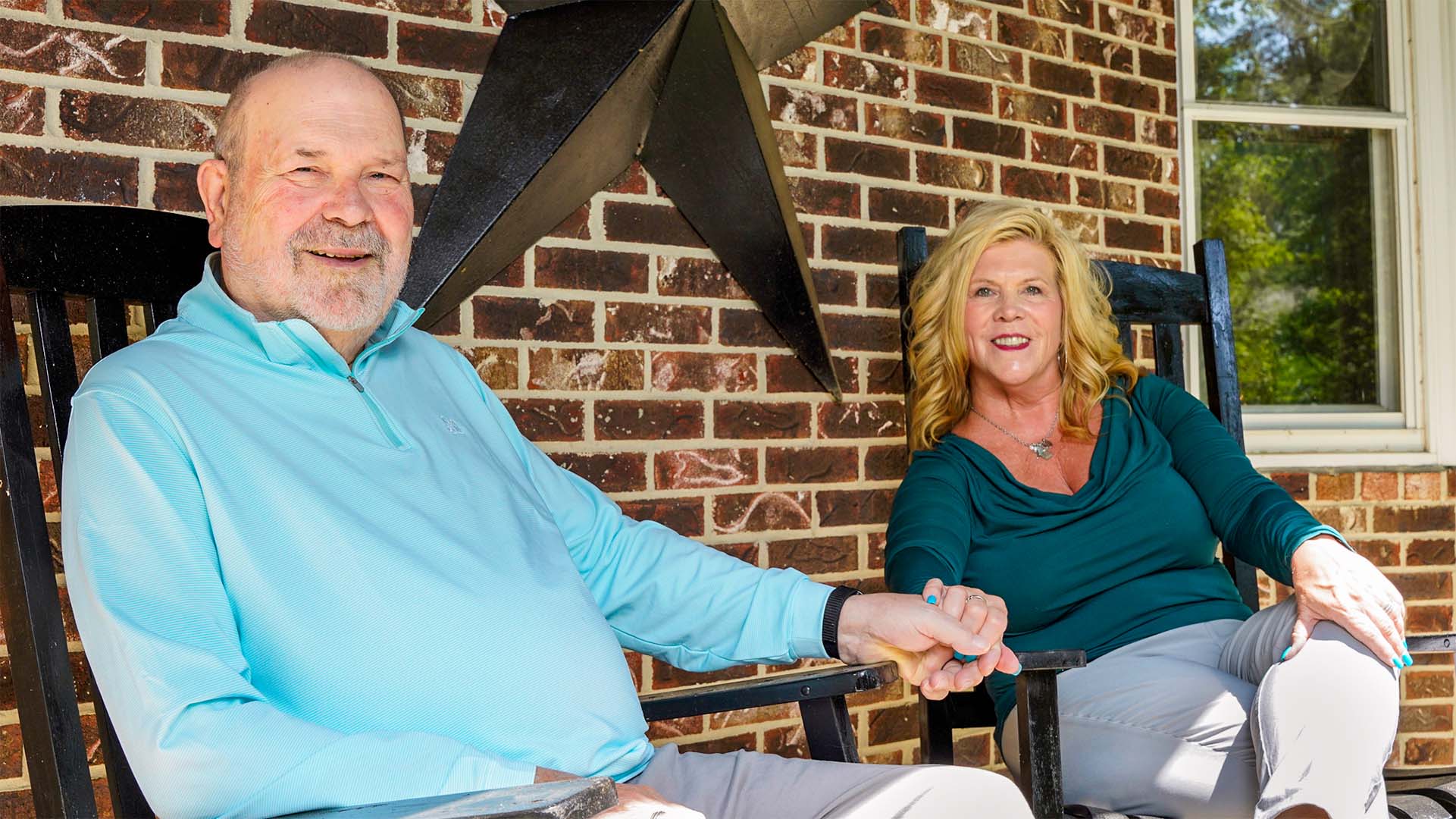 Robert and Allyson holding hands on their porch.